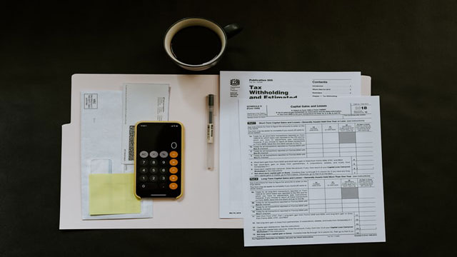 a folder on a desk with tax papers inside and a cup of coffee and calculator